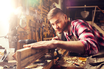 Image showing carpenter working with wood plank at workshop