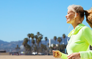 Image showing woman with earphones running over venice beach