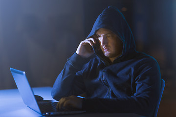 Image showing hacker with laptop calling on cellphone
