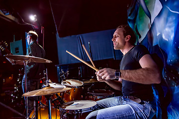 Image showing Drummer playing on drum set on stage.