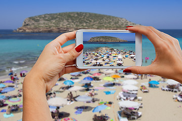 Image showing Young girl with mobile phone photographs Cala Conta beach in Ibi