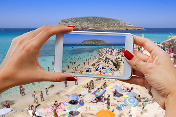 Image showing Young girl with mobile phone photographs Cala Conta beach in Ibi