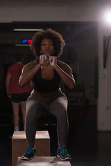 Image showing black female athlete is performing box jumps at gym