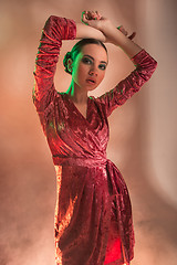 Image showing High Fashion model woman in colorful bright lights posing in studio,