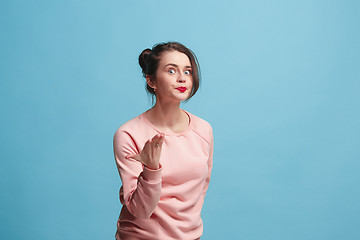 Image showing Beautiful female half-length portrait isolated on blue studio backgroud. The young emotional surprised woman