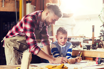 Image showing happy father and son with blueprint at workshop