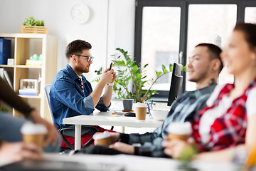 Image showing creative man with smartphone at office