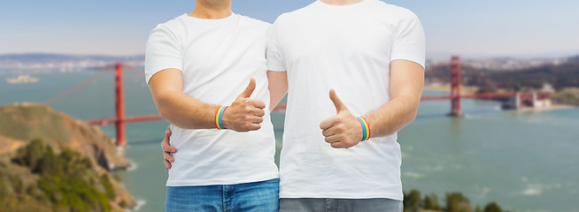 Image showing gay couple with rainbow wristbands shows thumbs up