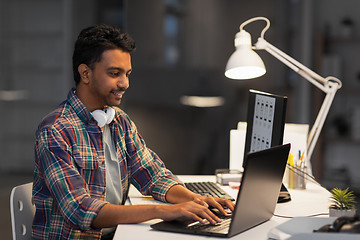 Image showing creative man with laptop working at night office