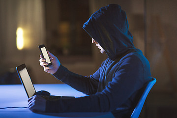 Image showing hacker with laptop and smartphone in dark room