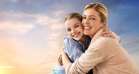 Image showing happy smiling mother hugging daughter over sky