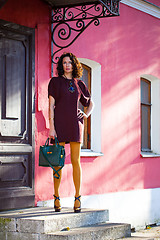 Image showing beautiful woman in a burgundy dress with a green hand bag