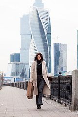 Image showing Beautiful business woman in a long light coat comes with a case 