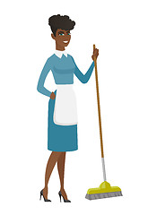 Image showing Young housemaid sweeping floor with a broom.