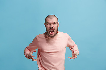 Image showing The young emotional angry man screaming on blue studio background