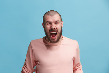 Image showing The young emotional angry man screaming on blue studio background