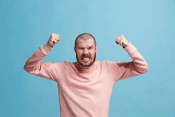 Image showing The young emotional angry man screaming on blue studio background