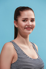 Image showing The happy woman standing and smiling against blue background.