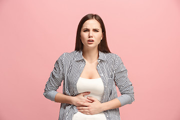 Image showing The stomach ache. The sad woman with stomach ache or pain on a pink studio background.