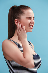 Image showing The Ear ache. The sad woman with headache or pain on a blue studio background.