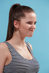 Image showing The young woman is looking angry on the blue background.