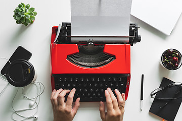 Image showing Woman hand working with bright red vintage typewriter