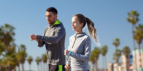 Image showing couple with fitness trackers running outdoors