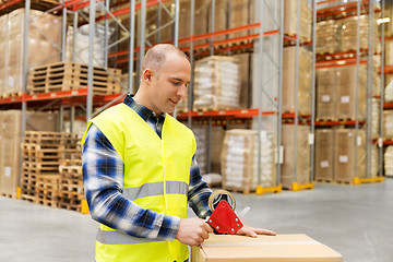 Image showing warehouse worker packing parcel with scotch tape