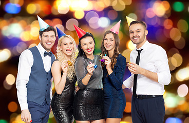 Image showing happy friends with party blowers over lights