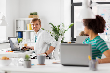 Image showing happy creative workers with laptops at office