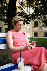 Image showing Adult woman using smartphone on bench