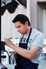 Image showing Barista pouring milk in cup