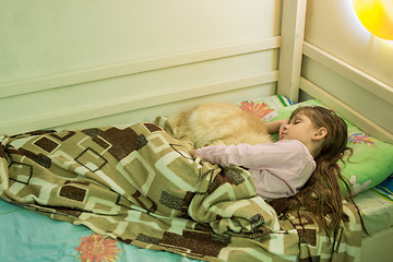 Image showing The girl sleeps in bed with a domestic cat