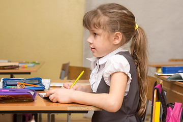 Image showing A girl first-graders attentively listens to the teacher at school