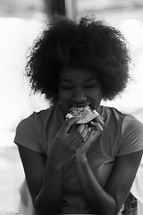 Image showing woman with afro hairstyle eating tasty pizza slice