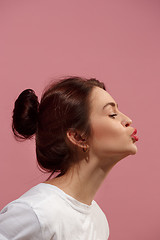 Image showing Portrait of attractive cute girl with bright makeup with kiss isolated over pink background