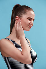 Image showing The Ear ache. The sad woman with headache or pain on a blue studio background.