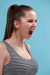 Image showing The young woman is looking angry on the blue background.