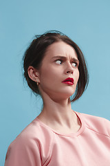 Image showing Let me think. Doubtful pensive woman with thoughtful expression making choice against blue background