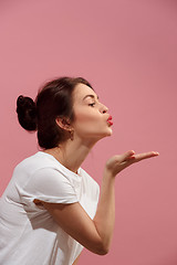 Image showing Portrait of attractive cute girl with bright makeup with kiss isolated over pink background