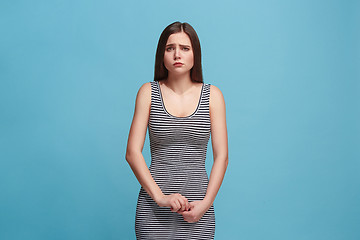 Image showing The awkward woman standing and looking at camera against blue background.