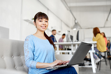 Image showing happy asian woman with laptop working at office