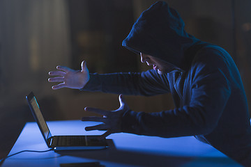 Image showing angry hacker with laptop computer in dark room