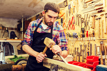 Image showing carpenter with wood, hammer and chisel at workshop