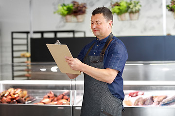 Image showing seller at fish shop writing to clipboard