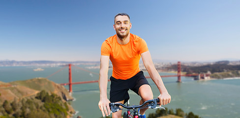 Image showing happy man riding bicycle over golden gate bridge