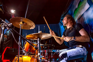 Image showing Drummer playing on drum set on stage.