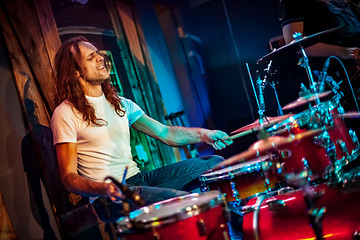 Image showing Drummer playing on drum set on stage.