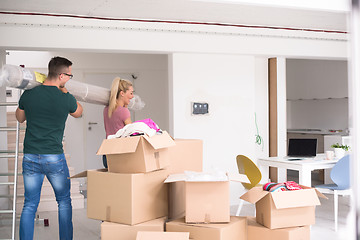 Image showing couple carrying a carpet moving in to new home