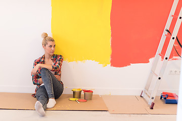 Image showing young female painter sitting on floor